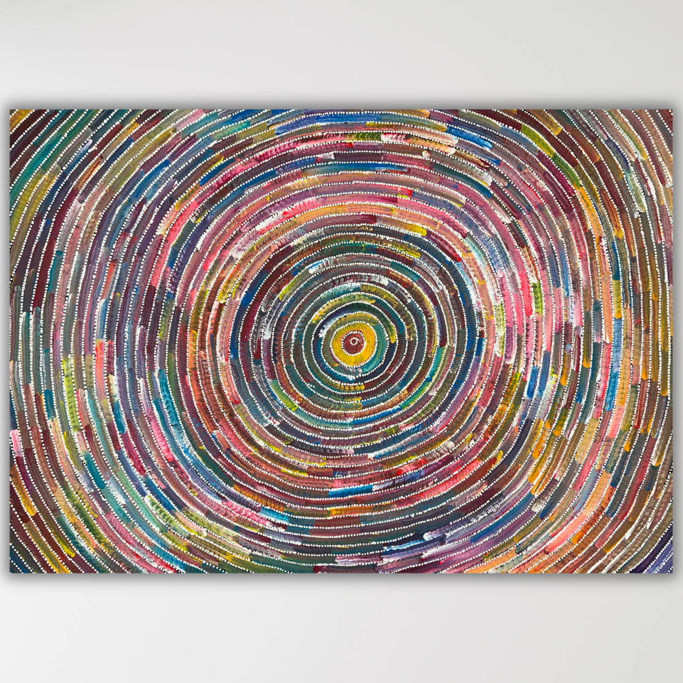 "Circle of Life" Bernadine Johnson Kemarre 100cm x 71cm featuring a vibrant, multicoloured concentric circular rings radiating from a central yellow and red point, shown against a light gray background.