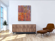 Load image into Gallery viewer, Modern interior with wooden sideboard, brown chair, and colorful Aboriginal painting on white wall.