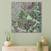 Load image into Gallery viewer, Indigenous artwork with green and purple tones on a light green wall above a wooden console table.
