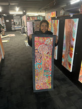 Load image into Gallery viewer, Photo of Bernadine Johnson Kemarre holding her Bush Flowers painting inside the Art by Farquhar Aboriginal Art Gallery, Edwardstown.
