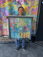 Load image into Gallery viewer, Photo of artist Bernadine Johnson Kemarre holding her Bush Flowers painting inside Art by Farquhar Aboriginal Art Gallery, Adelaide.
