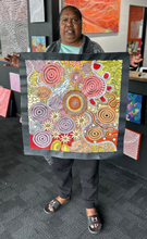 Load image into Gallery viewer, Julieanne Nungurrayi Turner holding her Budgerigar Dreaming painting in the gallery.
