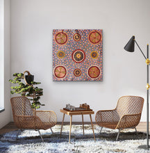 Load image into Gallery viewer, Lynette Conway Bush Flower Painting, purple, yellow, red, orange, white dot painting. Living room with wicker chairs, a small table with chessboard, and a colorful abstract painting on the wall.
