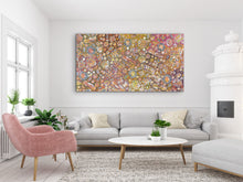 Load image into Gallery viewer, Living room with a colorful &quot;Bush Yam Dreaming&quot; Rochelle Bird Mbitjana 198cm x 110cm painting on the wall, gray sofa, pink armchair, and coffee table.

