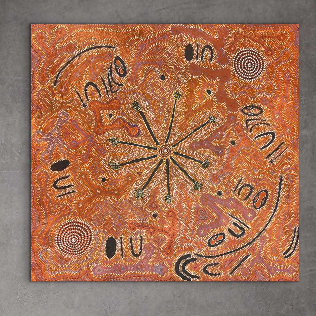 A piece of Aboriginal artwork featuring a central bushfire design with surrounding patterns and text. 