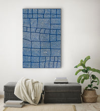 Load image into Gallery viewer, Blue Australian patterned artwork on a white wall above a gray bench with a plant to the right.
