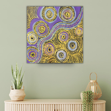 Load image into Gallery viewer, Indigenous artwork with circular patterns in purple and yellow on a light green wall above a wooden console table.
