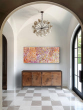 Load image into Gallery viewer, Foyer with a chandelier, wooden sideboard, and colorful Aborignal painting.
