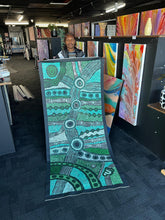 Load image into Gallery viewer, Clarise Tunkin holding the Minyma Malilu painting in the gallery showing scale and colour richness.
