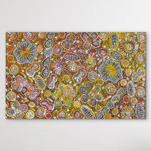 Load image into Gallery viewer, Aboriginal Painting yellow, orange, red shown on white wall, with flowers
