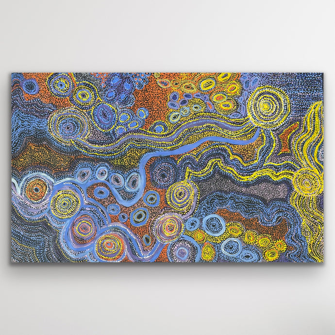 Rich blues and desert gold tones flow across the canvas in Rhoda Tjitayi’s depiction of the sisters’ Dreaming story.