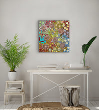 Load image into Gallery viewer, Colorful Aboriginal painting on a wall above a white desk with plants and decor.
