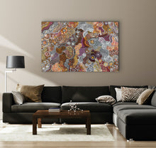 Load image into Gallery viewer, Living room with a black sectional sofa, wooden coffee table, and a colourful Aboriginal Janet Golder Kngwarreye holding her 180x116cm painting on the wall.
