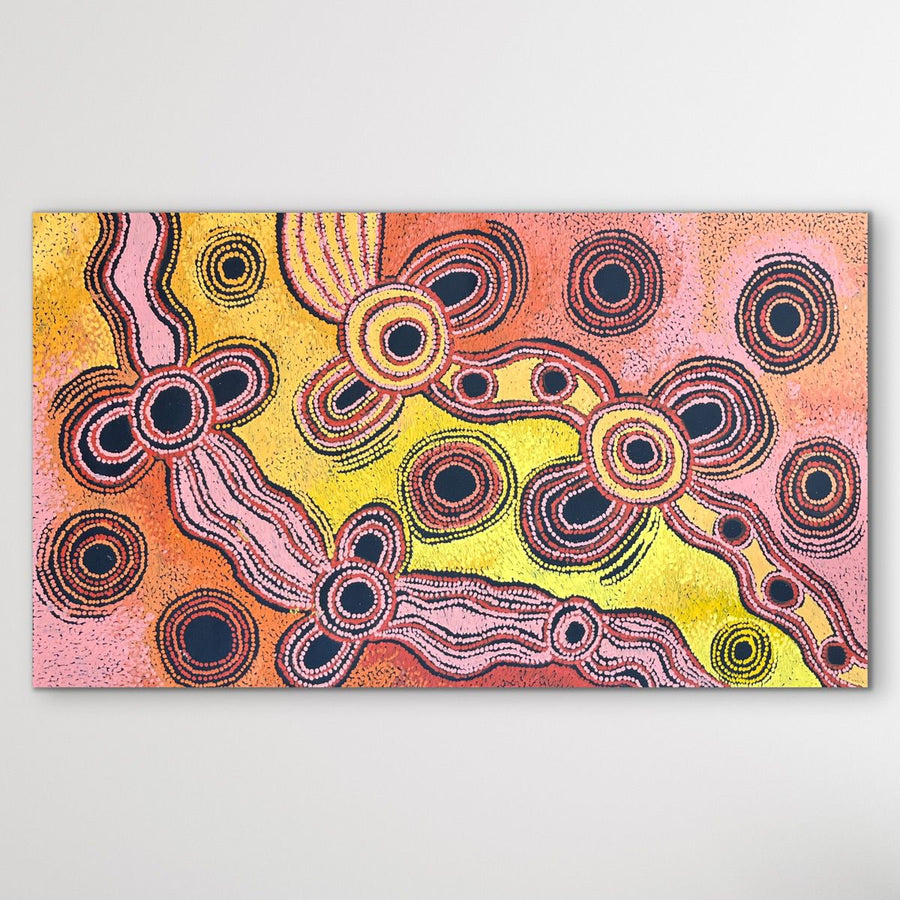 Aboriginal art piece with circular patterns on a pink and yellow with black background